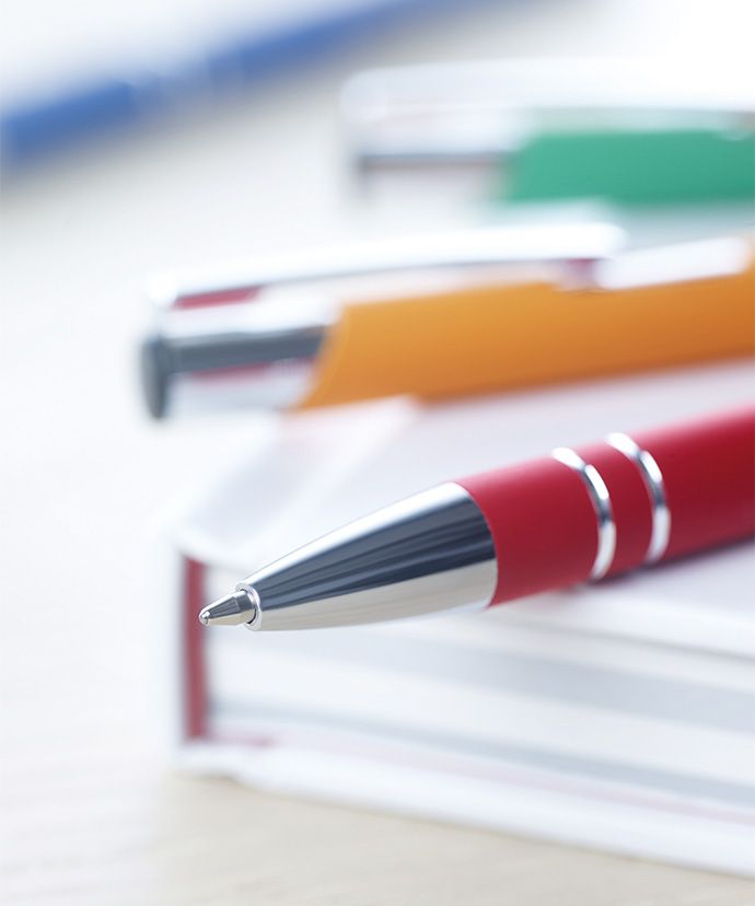 Metallpenner i ulike farger som ligger på en bok