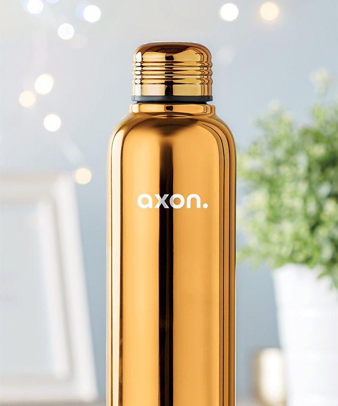 Gullfarget termos med trykk og en plante i bakgrunnen. Profileringsartikkel til vinteren.